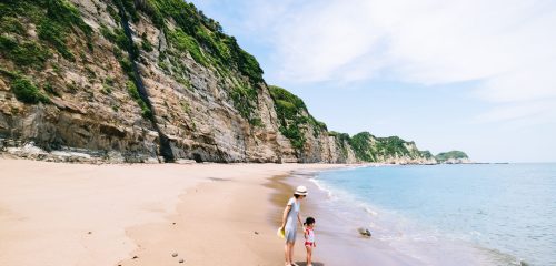 Mother and her little girl having fun on a deserted beach with cliff, Chiba, Japan